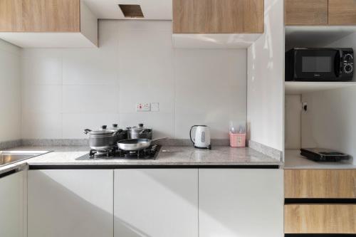 a kitchen with white cabinets and a stove with pots and pans at Firenze Apartments Lekki in Lagos
