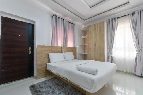 a white bedroom with a large bed and a window at Firenze Apartments Lekki in Lagos