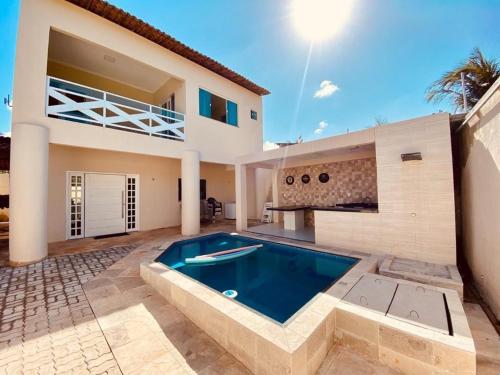 a villa with a swimming pool in front of a house at Casa em flecheiras com piscina in Flecheiras