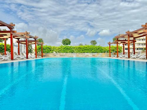 einen großen blauen Pool mit weißen Stühlen und Bäumen in der Unterkunft Best Western Plus Khan Hotel in Antalya