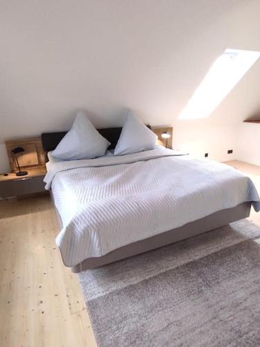 a bedroom with a bed with white sheets and pillows at Haus im Erholungsgebiet Detern in Detern