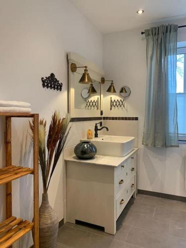 a white bathroom with a sink and a window at Haus im Erholungsgebiet Detern in Detern