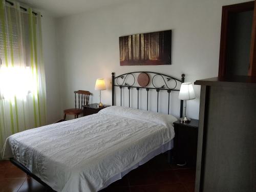 1 dormitorio con 1 cama blanca y 2 lámparas en EL VIEJO OLMO, en Herguijuela de la Sierra