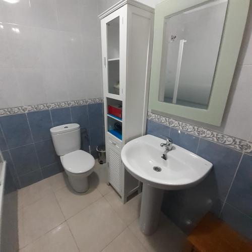 a bathroom with a white toilet and a sink at EL VIEJO OLMO in Herguijuela de la Sierra