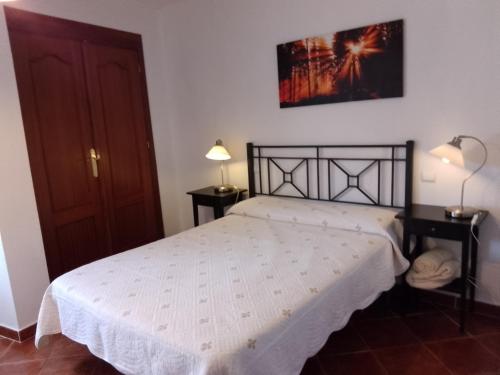a bedroom with a bed with a white bedspread at EL VIEJO OLMO in Herguijuela de la Sierra