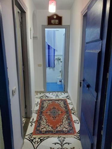 a hallway with a blue door and a rug on a floor at Studio Skanes in Monastir