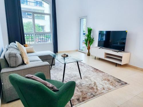 a living room with a couch and a tv at Harf-G13 Fancy 1BR w big balcony at Ansam , Yas Island in Abu Dhabi