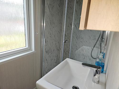 a white sink in a bathroom with a window at Pods 1 and 2 Willow Bank in Market Rasen