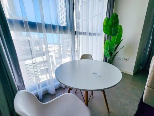 een witte tafel en stoelen in een kamer met een raam bij Harf3502 Luxurious Large Studio in Abu Dhabi
