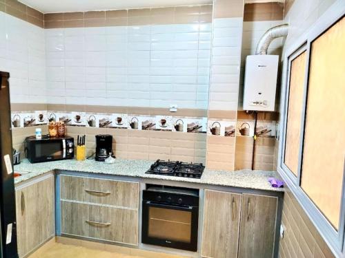 Il comprend une cuisine équipée d'une cuisinière et d'un comptoir. dans l'établissement Résidence Inaya, à Oran