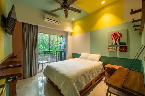 a bedroom with a bed and a desk and a window at Marala Hotel in Esterillos