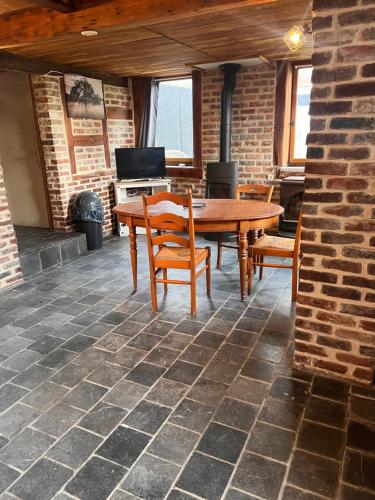 a dining room with a table and chairs and a brick wall at Welkom huis in Eecke