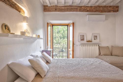 ein weißes Schlafzimmer mit einem großen Bett und einem Fenster in der Unterkunft Appartamenti Anguria Toscana in Sinalunga