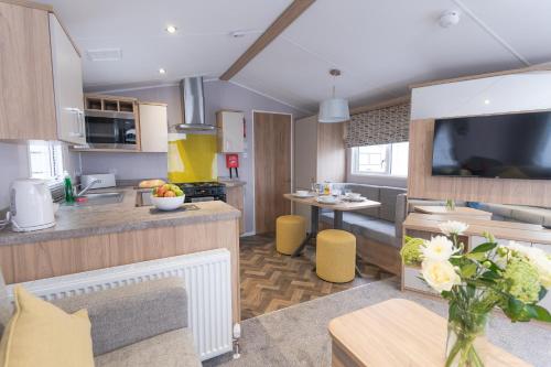 a kitchen and living room with a vase of flowers at Marine Holiday Park in Rhyl