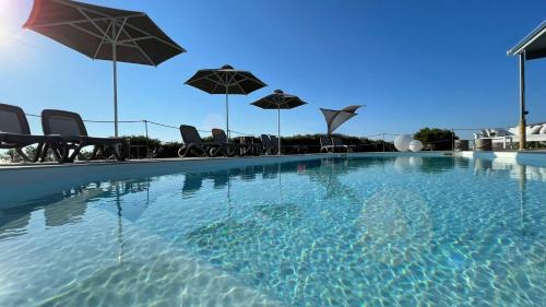 a swimming pool with chairs and umbrellas at Hermoso Luxury Suites in Monolithos