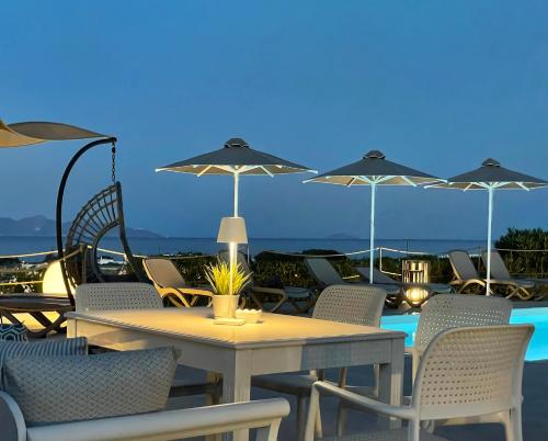 un patio con tavolo, sedie e ombrelloni di Hermoso Luxury Suites a Monolithos