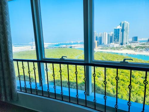 a window with a view of the beach and buildings at Huge water front 1BR Apt with 2 Sofa Beds+King Bed in Alreem Island in Abu Dhabi