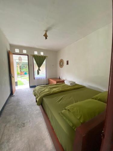 a bedroom with a green bed and a table at Rago's Homestay in Kelimutu