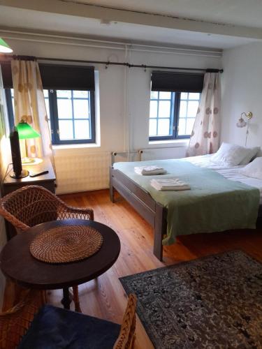 a bedroom with a bed and a table and two windows at Wiikki Majatalo in Viitasaari