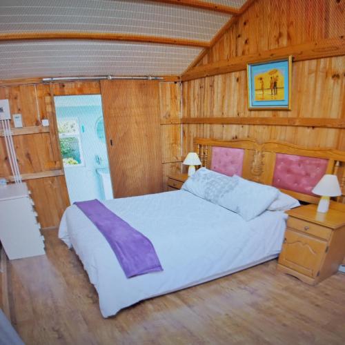1 dormitorio con cama blanca y paredes de madera en Elly's Place bnb, en Darling