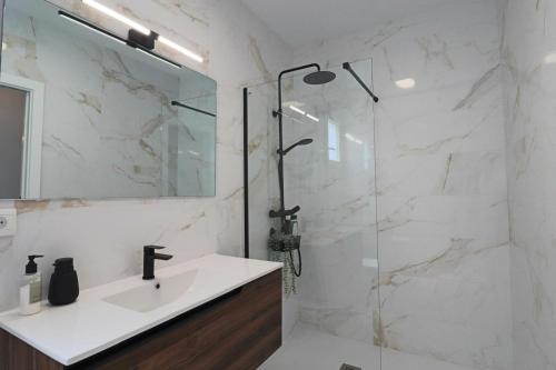 uma casa de banho com um lavatório e uma cabina de duche em vidro. em Apartamento Estrella Sol em Cartaya