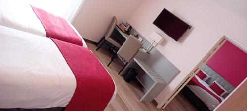 1 dormitorio con 1 cama y escritorio con TV en Logis Hôtel Le Moulin de la Coudre, en Venoy