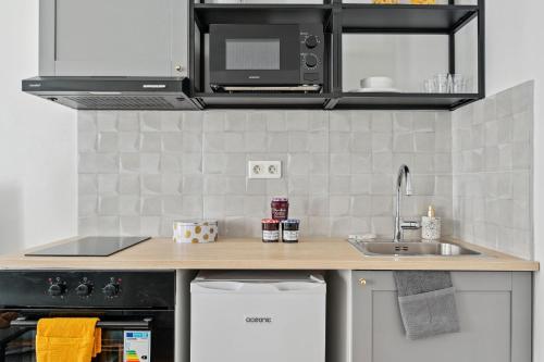 eine Küche mit einer Spüle und einer Mikrowelle in der Unterkunft Le Marais - CityApartmentStay in Paris