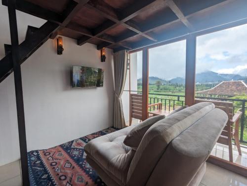 a living room with a couch and a large window at Cottage Linggayoni Dieng 1 in Dieng