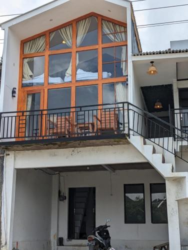 une maison avec un balcon et une moto garée devant dans l'établissement Cottage Linggayoni Dieng 1, à Diyeng