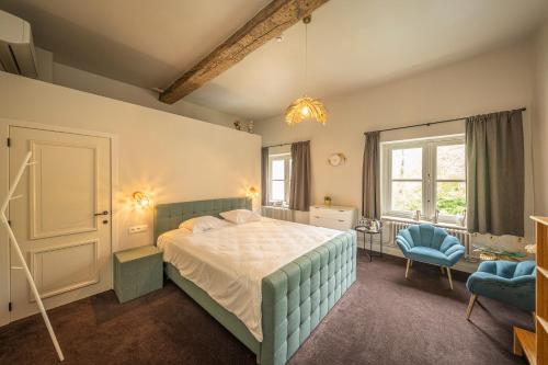een slaapkamer met een bed en een blauwe stoel bij Leyselebeke Castle in Brugge