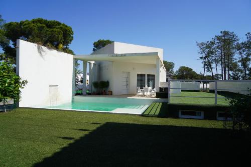una casa bianca con piscina nel cortile di Chalet blanco con piscina privada a Isla Cristina