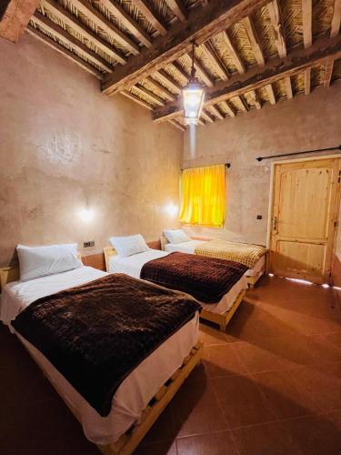 a bedroom with two beds in a room with a window at Camping auberge palmeraie d'amezrou in Zagora