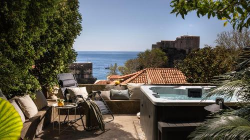 un patio con bañera de hidromasaje, mesa y sillas en Dubrovnik Old Town Apartments, en Dubrovnik