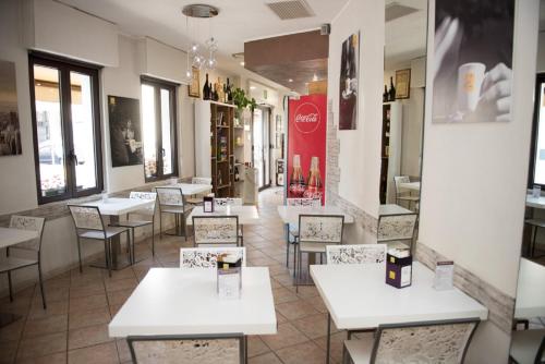 un ristorante con tavoli e sedie bianchi e finestre di Il Ragno D`Oro a Rho