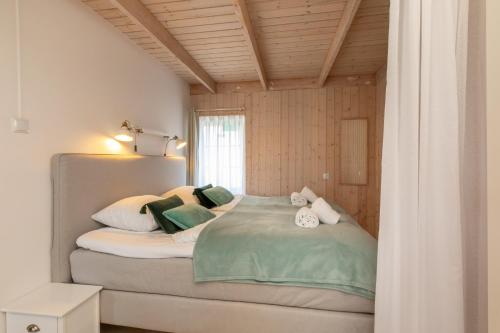 um quarto com uma cama com almofadas verdes e brancas em Molenweg 27a em Zoutelande