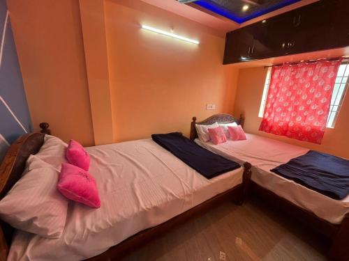 two beds in a room with pink pillows at PANMOZHI RESIDENCY in Tiruvannāmalai