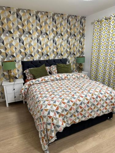 a bedroom with a large bed with a colorful bedspread at Coxwell in Mill Hill