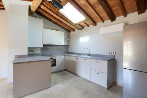 une cuisine avec des armoires blanches et un évier dans l'établissement La Résidence Opale, à Lagrasse