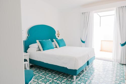 a bedroom with a blue and white bed with blue pillows at Hotel Conca d'Oro in Positano