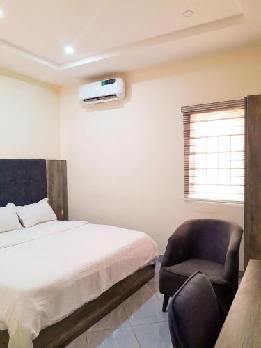 een slaapkamer met een bed en een stoel bij Come Inn Hotel in Rubuchi