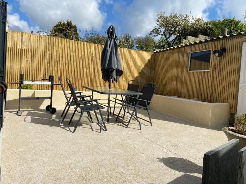 uma mesa com cadeiras e um guarda-sol e uma cerca em Gîte Ty Rest à 8 mn de la plage em Brengovel