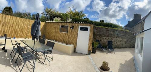 um pátio com uma mesa e cadeiras e um barracão em Gîte Ty Rest à 8 mn de la plage em Brengovel