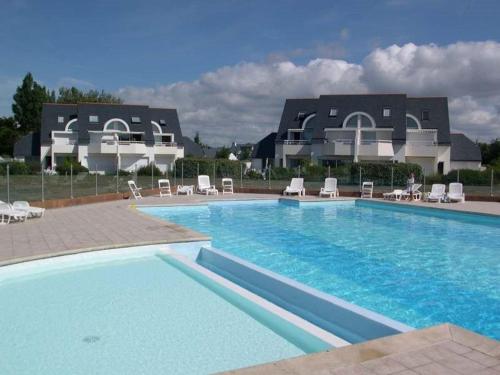 une grande piscine avec des chaises et un bâtiment dans l'établissement Appartement Duplex 50m² à Carnac avec Piscine Chauffée, Proche Plages pour 6 Personnes - FR-1-477-63, à Carnac