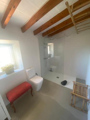 une salle de bain blanche avec des toilettes et un tabouret rouge dans l'établissement Finca Na Moreta, à Felanitx