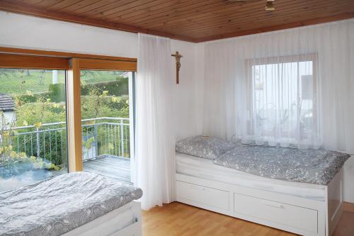- une chambre avec un lit et un balcon avec une croix dans l'établissement Wendelin`s Ferienwohnung, à Wolfegg
