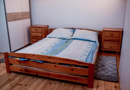 a bedroom with a wooden bed and two night stands at Apartament EmKa z tarasem Rowy in Rowy