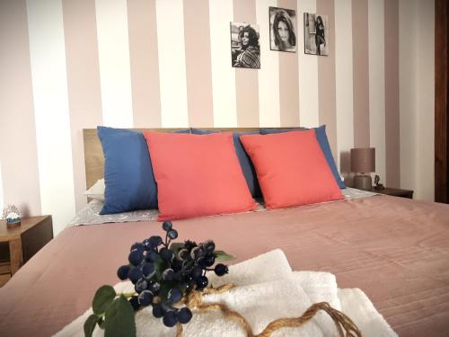 1 dormitorio con 1 cama con almohadas rojas y azules en Arborea Studio Apartment, en Porto Torres