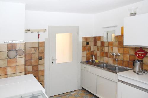 - une cuisine avec des placards blancs et un évier dans l'établissement Wendelin`s Ferienwohnung, à Wolfegg