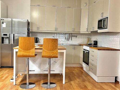 a kitchen with white cabinets and two chairs at a counter at City Center Residence - 64 m2 St Eriksplan in Stockholm