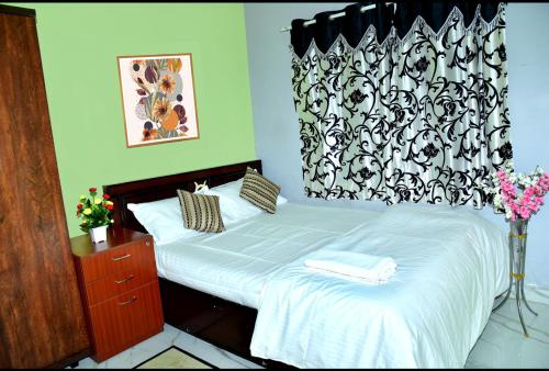a bed with white sheets and a black and white curtain at Royal Guest House in Chikmagalūr